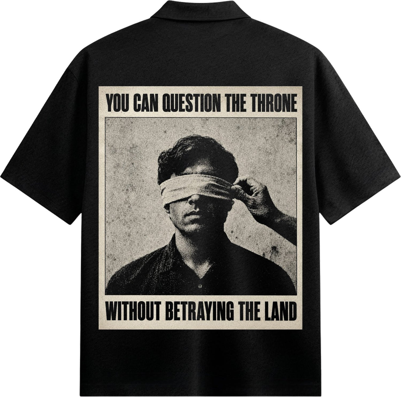 A black and white graphic on a black shirt shows a man blindfolded with a hand adjusting the blindfold set against a textu...
