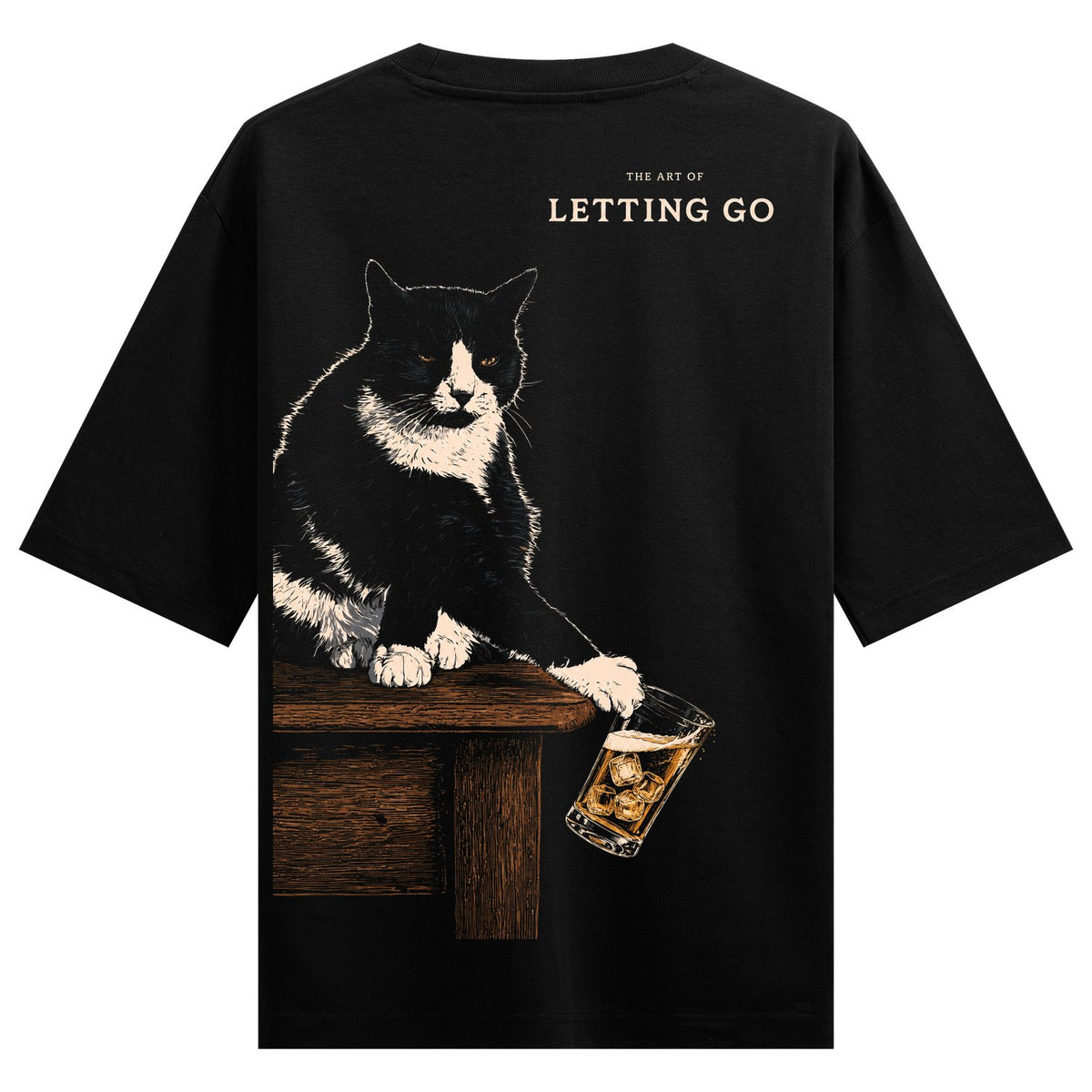 Cat Letting Go Oversized T-Shirt — a black and white cat sits on a wooden table holding a whiskey glass with ice cubes, text