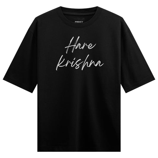 White cursive script spelling Hare krishna is centered on a plain black short-sleeved t-shirt on PRDGY oversized t-shirt